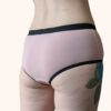A back view of a model wearing the Constellation Panty Pattern in light pink fabric with black elastic.